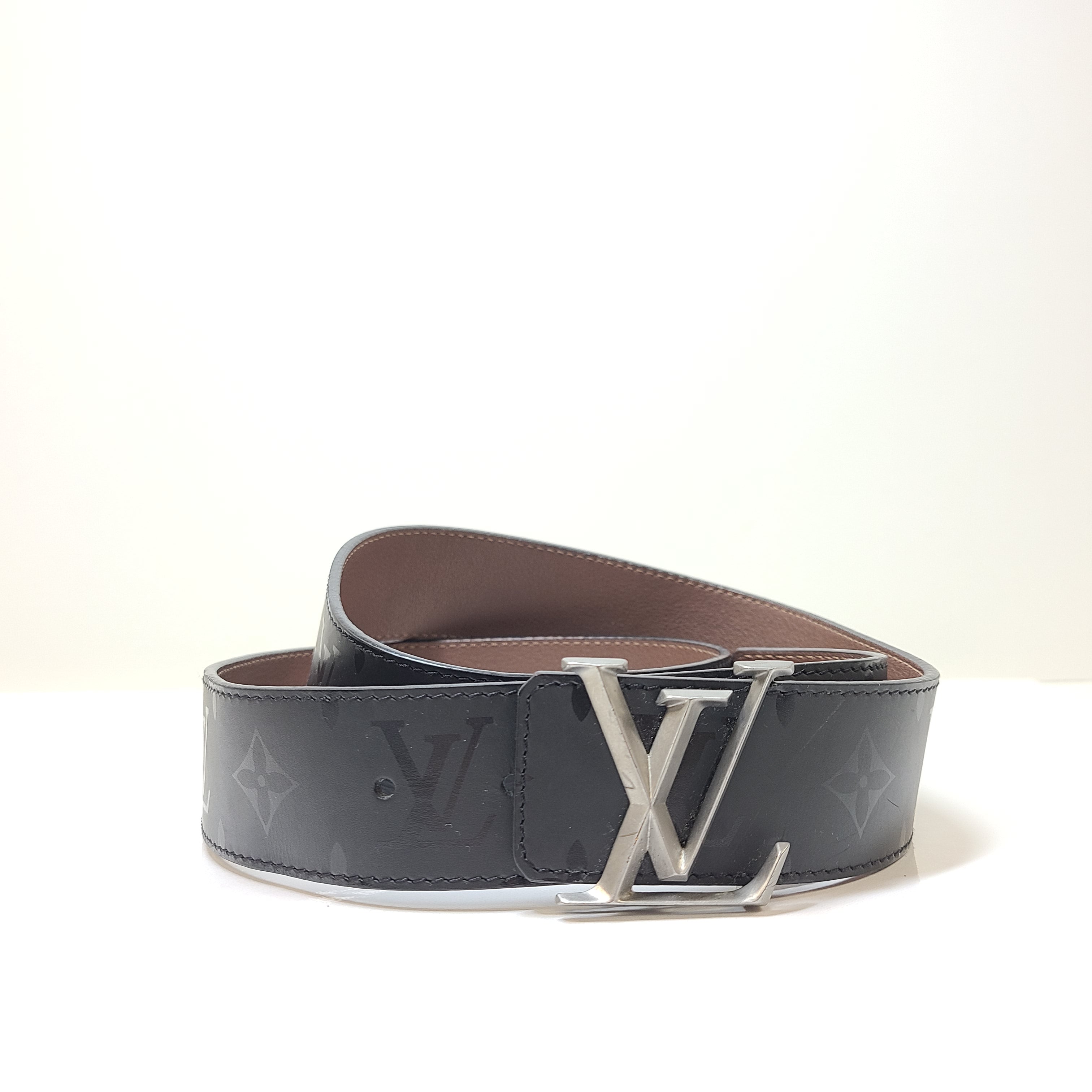 A black Louis Vuitton leather belt with monogram pattern, polished buckle, and Louis Vuitton Paris stamp.