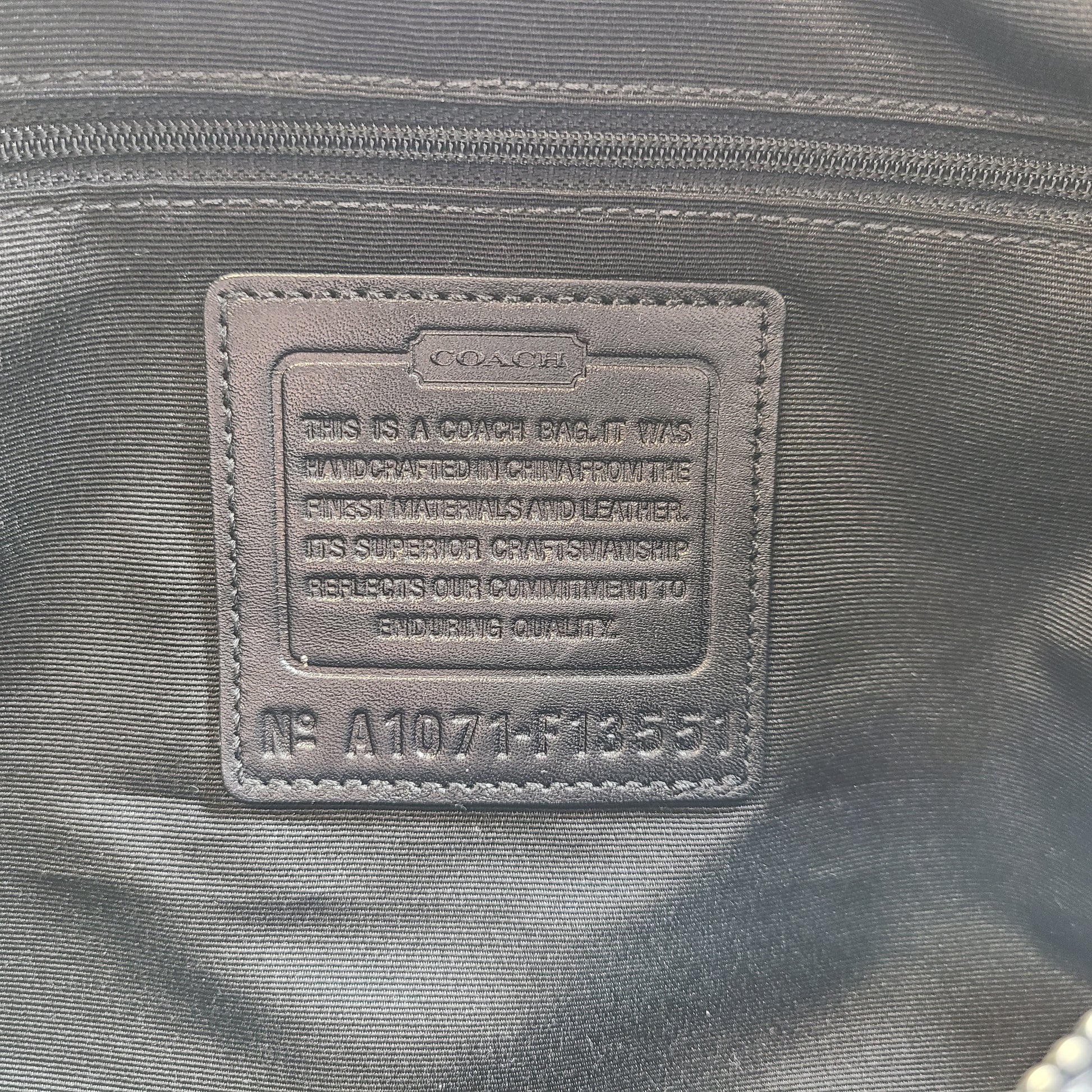 Gray and black Coach satchel with double handles, zip closure, and an interior patch stating handcrafted Coach leather.