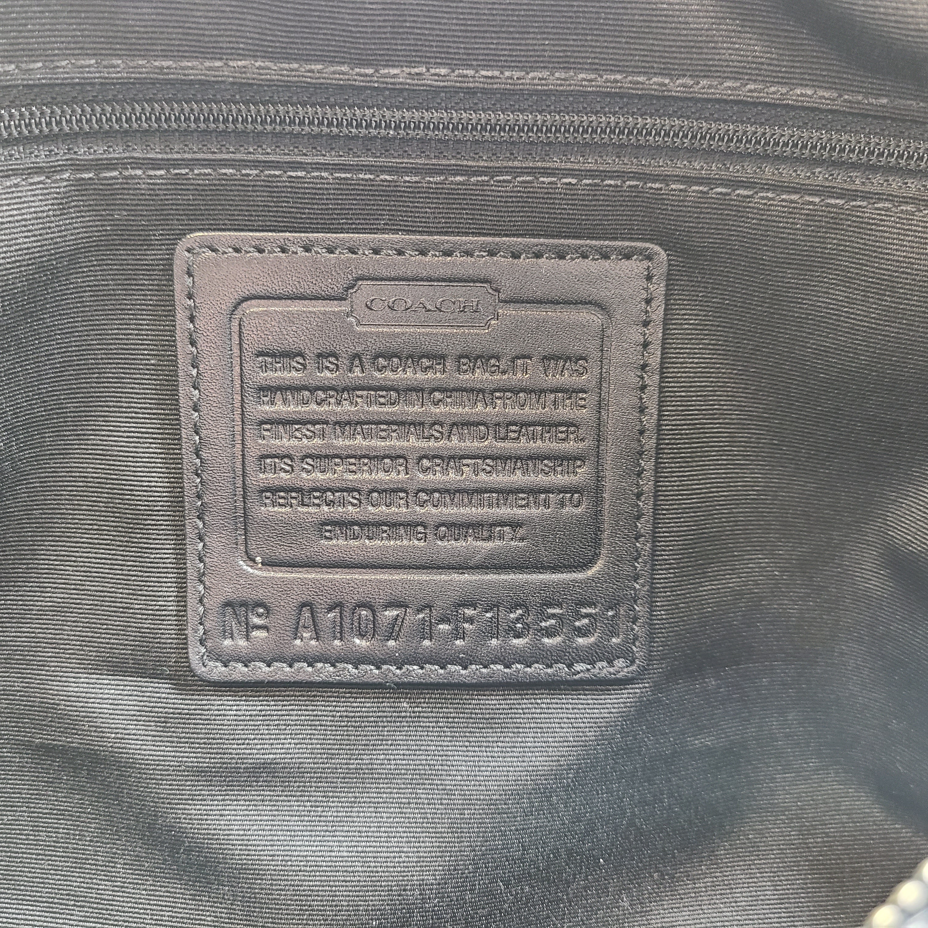 Gray and black Coach satchel with double handles, zip closure, and an interior patch stating handcrafted Coach leather.