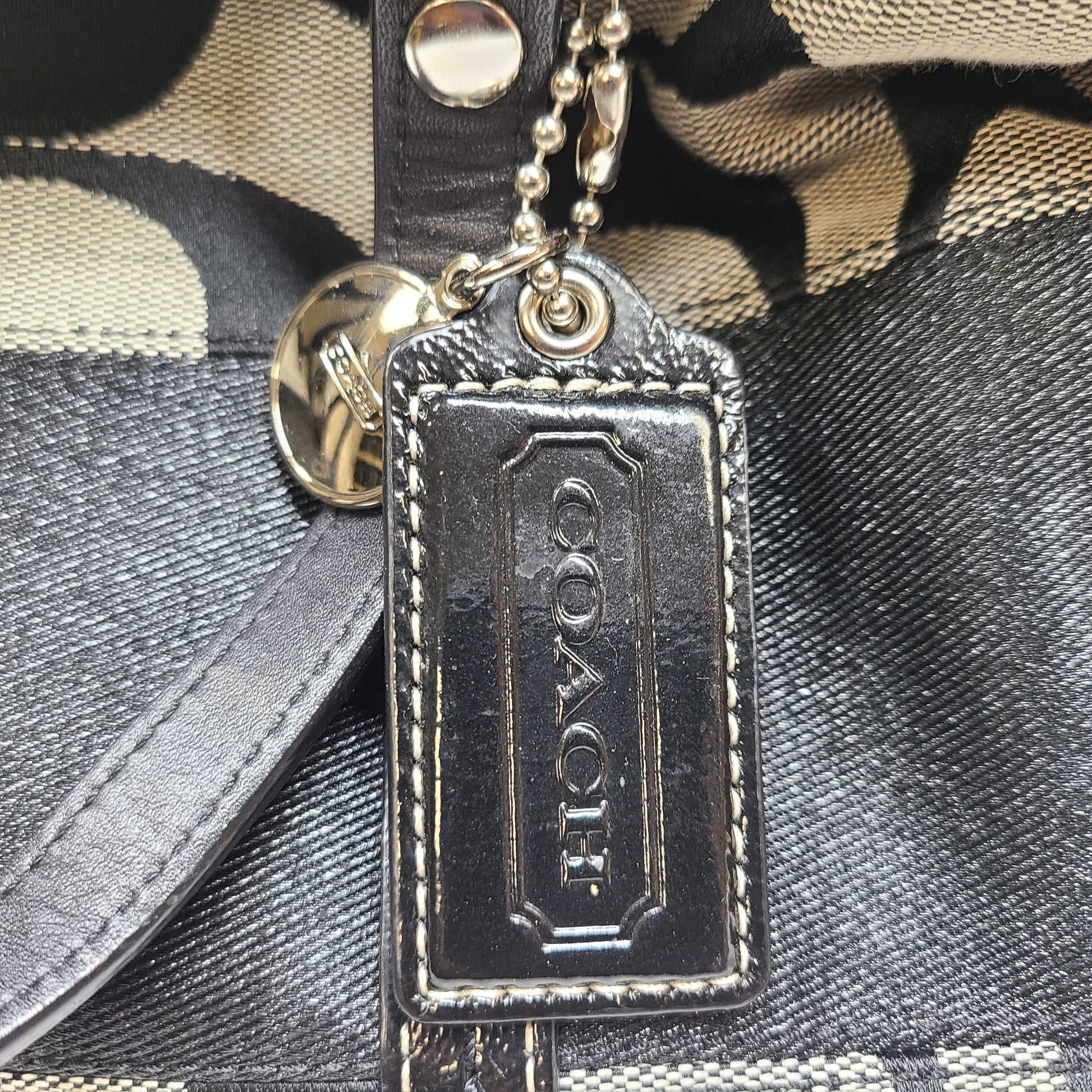 Gray and black Coach satchel with double handles, zip closure, and an interior patch stating handcrafted Coach leather.