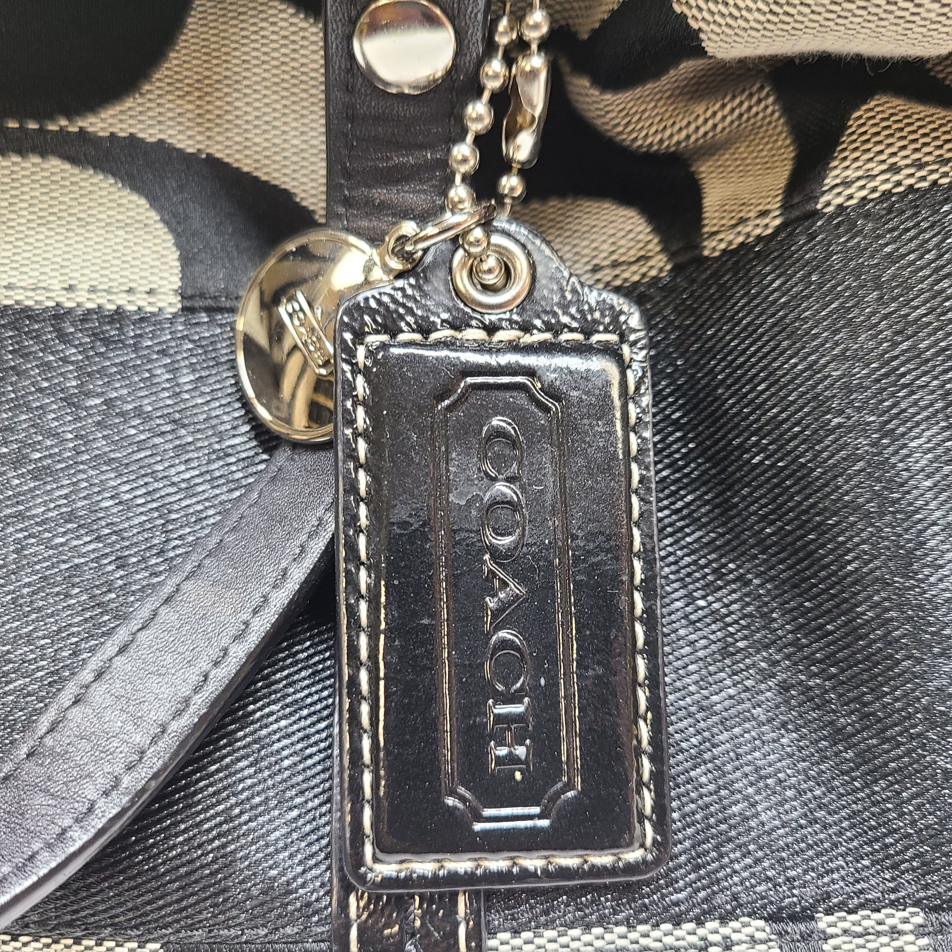 Gray and black Coach satchel with double handles, zip closure, and an interior patch stating handcrafted Coach leather.