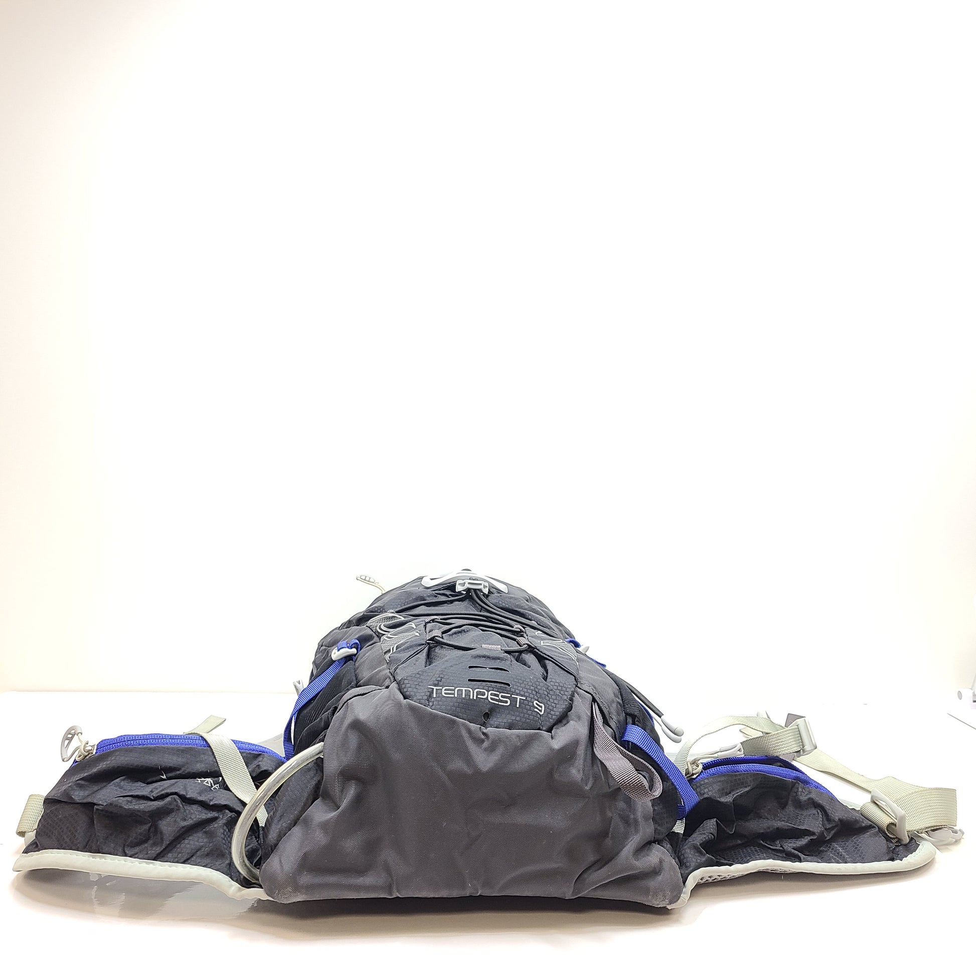 Compact Osprey Tempest 9 backpack in black, blue, and grey with Airscape back panel and adjustable straps for comfortable carry.